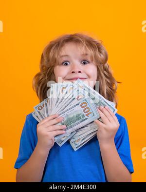 Capretto che mostra le fatture del dollaro dei soldi, levante in piedi sognante dei ricchi contro lo sfondo isolato dello studio. Foto Stock