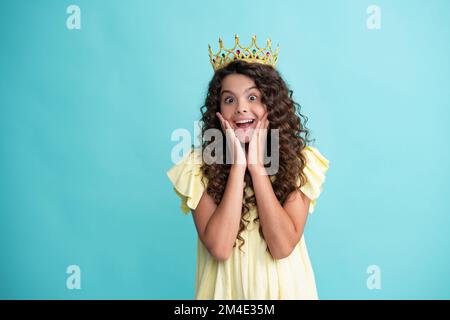 Piccola regina che indossa la corona d'oro. Ragazza adolescente principessa che tiene corona tiara. PROM partito, concetto di infanzia. Felice adolescente, positivo e sorridente Foto Stock