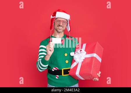 buon regalo di natale. uomo in possesso di carta di debito per lo shopping. felice uomo in costume di elfo Foto Stock