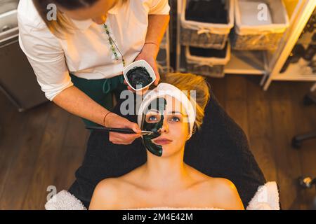 Estetista che applica la maschera facciale su un volto di una donna. Foto di alta qualità Foto Stock