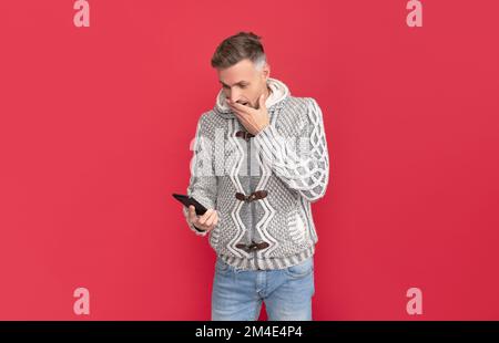 stupito uomo controllare la posta elettronica sul telefono. modello di moda maschile tenere smartphone. Foto Stock