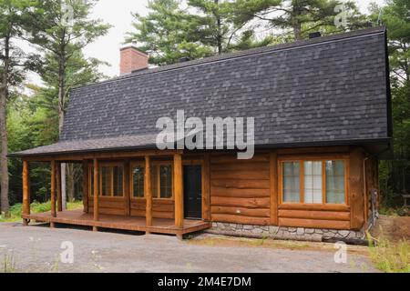 Casa in legno in stile cottage ibrido con tetto mansardato in asfalto sfumato grigio. Foto Stock