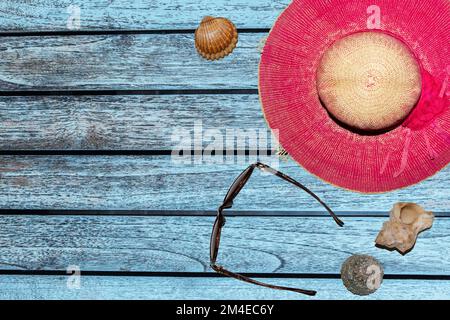 striscioni per la pubblicità occhiali da cappello conchiglie su uno sfondo di legno di colore blu Foto Stock