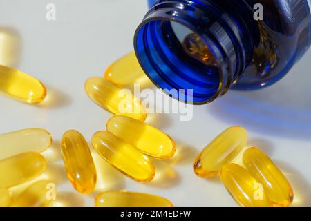 Olio di pesce Omega 3 fuoriuscita dalla bottiglia contro sfondo di marmo bianco, concetto di alimentazione sana, prevenzione delle malattie, e trattamento. Prendendo supplemento Foto Stock