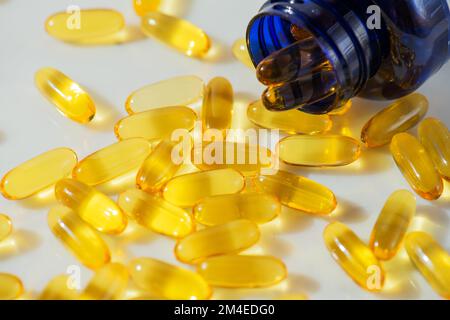 Olio di pesce Omega 3 fuoriuscita dalla bottiglia contro sfondo di marmo bianco, concetto di alimentazione sana, prevenzione delle malattie, e trattamento. Prendendo supplemento Foto Stock