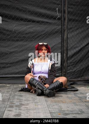 Medellin, Antioquia, Colombia - Novembre 14 2022: Una donna colombiana con capelli rossi che indossa stivali lunghi neri è seduta sola sul pavimento Foto Stock