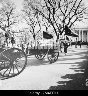 Un limbers e cassoni che portano la scrigno del presidente degli Stati Uniti John F. Kennedy visto spostare giù la guida della Casa Bianca sulla strada per St. Cattedrale di Matteo il 25 novembre 1963. Una guardia di colore che tiene i colori presidenziali, la bandiera del presidente degli Stati Uniti, e il cavallo senza rivali 'Black Jack', seguono dietro. Foto Stock