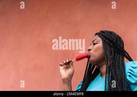 Giovane donna nera che mangia il papicolo nella città Foto Stock