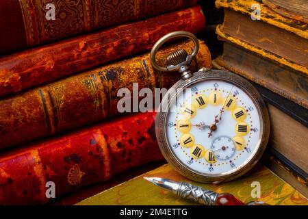 Bellissimo orologio da tasca vecchio e libri impilati con penna Still Life Foto Stock