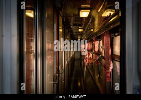 La cabina di prima classe dello Special Express 14 è visibile durante l'ora d'oro. I Backpackers cercano il loro posto prima di salire a bordo alla stazione ferroviaria di Chiang mai. Lo Special Express 14, una popolare linea turistica parte della flotta della ferrovia statale della Thailandia (SRT), effettua il suo viaggio notturno da Chaing mai (CNX) a Bangkok (BKK). Foto Stock