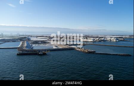 Fehmarn, Germania. 16th Dec, 2022. Accanto al porto di lavoro e al porto dei traghetti di Puttgarden (fotografia aerea scattata con un drone) si trova la fossa di scavo (M) per il portale del tunnel al tunnel di Fehmarnbelt. Il tunnel ferroviario e stradale di 18 km collegherà l'isola di Fehmarn e l'isola danese di Lolland dal 2029. Secondo Femern A/S, il costo è di 7,1 miliardi di euro. Credit: Christian Charisius/dpa/Alamy Live News Foto Stock