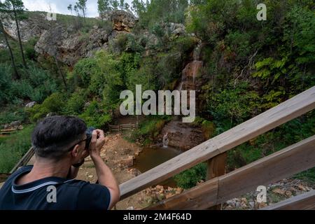Persona che fotografa la cascata da Fraga D'alta e il passaggio pedonale a Orvalho, Portogallo, Europa Foto Stock