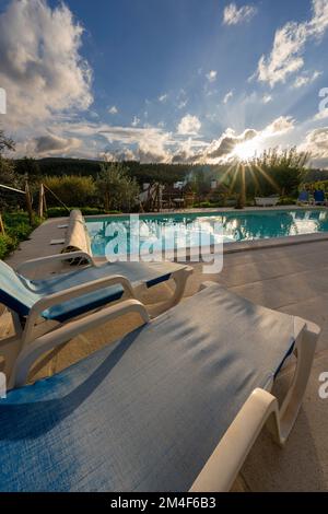 Lettini prendisole reclinabili accanto a una piscina all'aperto Foto Stock