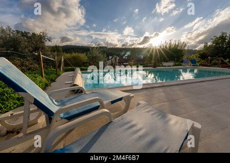 Lettini prendisole reclinabili accanto a una piscina all'aperto Foto Stock