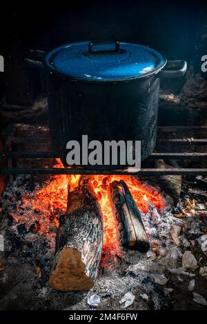 Coltiva mani irriconoscibili tenendo grande padella di ferro con brodo  bollente per cucinare la paella sul fuoco aperto con la legna — Anonimo,  Antichi - Stock Photo