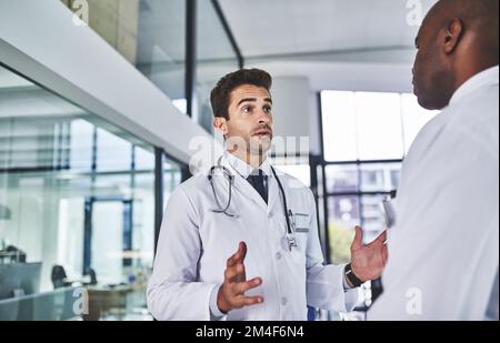 Dobbiamo prendere decisioni rapide in merito. due medici che hanno una discussione in un ospedale. Foto Stock
