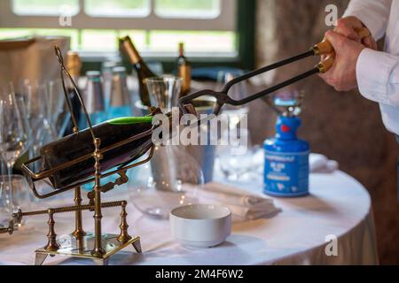 Sommelier apre una bottiglia di vino con pinze Porto bollenti rosse Foto Stock