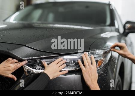 Primo piano rispetto alla procedura di installazione PPF su un faro anteriore . Il PPF è una pellicola di protezione della vernice che protegge la vernice da graffi e scheggiature. Concetto di: Protezione, protezione, auto, nuovo, lavoro. Foto Stock