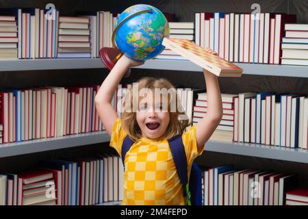 Ragazzo di scuola con mondo globo e scacchi, infanzia. Scolastica bambino che studia in classe alla scuola elementare. Bambino che studia sulla lezione in classe a. Foto Stock