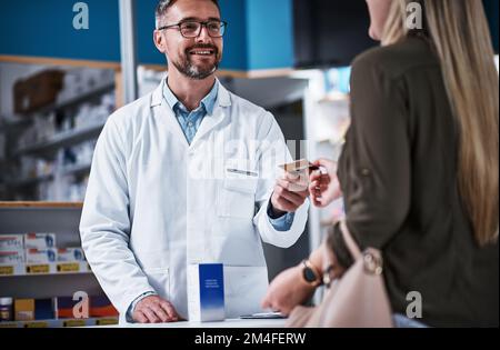 Lascilo appena scorrere quello per voi. una giovane donna che paga merce con carta di credito in farmacia. Foto Stock