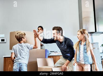 Dammi un alto cinque amici. un giovane padre affettuoso che dà un alto cinque a suo figlio mentre disimballano le scatole nella loro nuova casa. Foto Stock