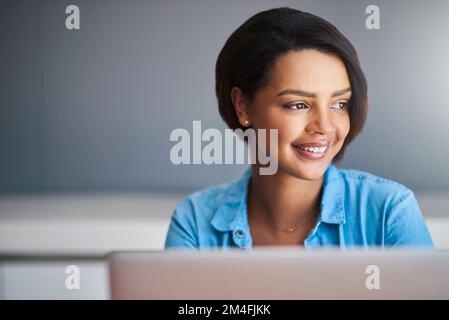 Una mente di imprenditori non smette mai di innovare. una giovane donna attraente che usa un notebook a casa su uno sfondo grigio. Foto Stock