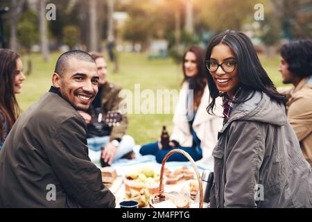 I nostri amici sono i migliori. Ritratto di due giovani allegri seduti a un pic-nic con gli amici fuori durante il giorno. Foto Stock