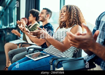 Basta un applauso. un gruppo di giovani colleghi di lavoro allegri seduti uno accanto all'altro mentre si stringono le mani all'interno del Foto Stock