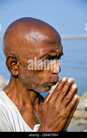Pellegrino che prega verso l'acqua del fiume santo Narmada Foto Stock