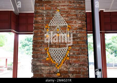 Phuang Malai mobile o tradizionale stile tailandese appeso fiori ghirlanda fatta a mano in plastica perlina di gelsomino su muro di mattoni di pietra per le persone visita pra Foto Stock