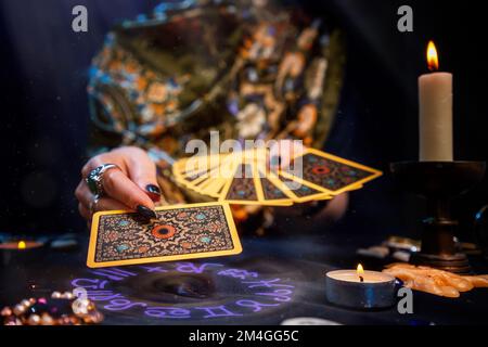 Il tessitore di fortuna tiene un ventilatore delle schede nelle sue mani e tiene fuori una scheda con una mano. Il cerchio astrologico si illumina a portata di mano. Primo piano. Il concetto Foto Stock