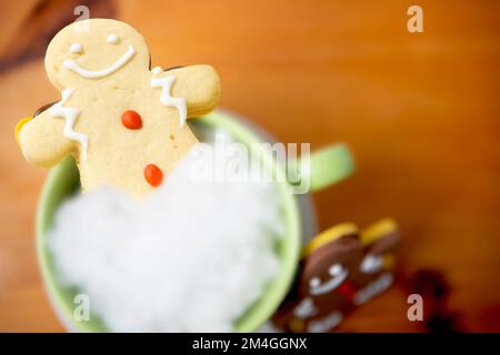 Biscotti di pan di zenzero in tazza di latte, visto dall'alto, sfondo di Natale, biscotti di Natale su legno Foto Stock