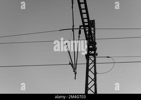 Una scala di grigi a basso angolo di una torre in acciaio con linee elettriche Foto Stock