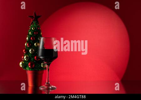 Albero di Natale con bicchiere di vino rosso. Capodanno o sfondo di Natale. Foto Stock