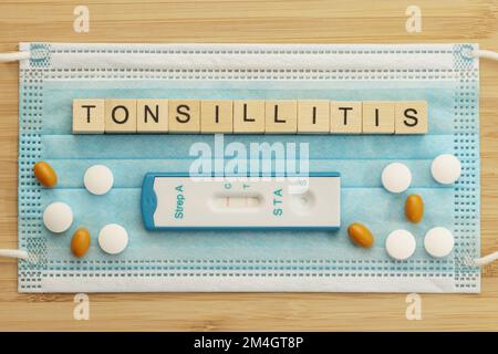 La parola Tolsillitis è rivestita con cubi di legno su una maschera chirurgica. Questa malattia batterica è causata da streptococchi. Un test rapido per il gruppo A st Foto Stock