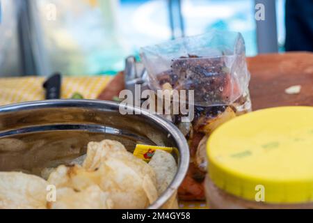 Patatine di mais giallo guarnite con carne macinata, guacamole, formaggio fuso, peperoni e foglie di coriandolo in piatto su tavola di legno messico latin americ Foto Stock