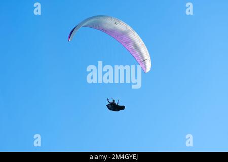 Batumi, Georgia - 28 2022 luglio: L'uomo vola su un parapendio e sventola la mano sullo sfondo di un cielo blu brillante Foto Stock