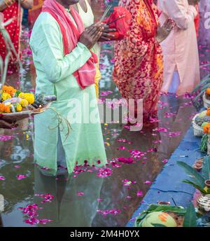 L'uomo devota con offerte religiose per Dio del sole durante la festa Chhath da un angolo piatto Foto Stock