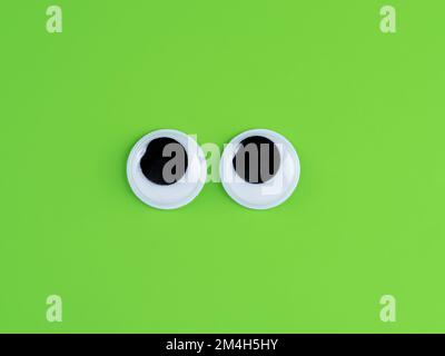 Googly cute occhi divertente isolato su luminoso verde lime sfondo copia logo spazio Foto Stock