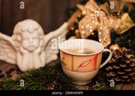 Angelo natalizio, tazza di caffè su un tavolo di legno scuro Foto Stock