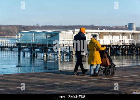 Gefrorenes Wasser an der Kieler Förde bei der Seebadeanstalt Düsterbrook ein Paar mit Kinderwagen geht vorbei Foto Stock