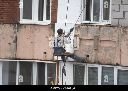 Tiraspol, Moldova - 10 dicembre 2022: Costruttore di alta quota isola la facciata di un edificio di appartamenti con plastica espansa. Casa isolante aerata Foto Stock