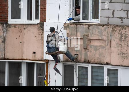 Tiraspol, Moldova - 10 dicembre 2022: Costruttore di alta quota isola la facciata di un edificio di appartamenti con plastica espansa. Casa isolante aerata Foto Stock