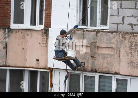 Tiraspol, Moldova - 10 dicembre 2022: Costruttore di alta quota isola la facciata di un edificio di appartamenti con plastica espansa. Casa isolante aerata Foto Stock