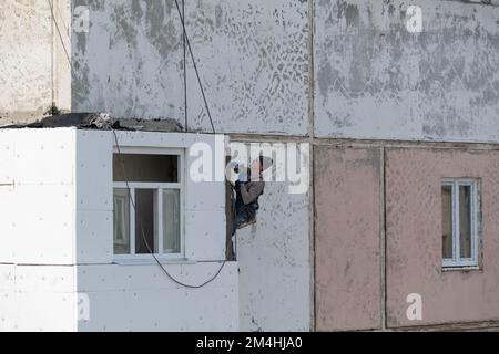 Tiraspol, Moldavia - 10 dicembre 2022: Isolamento della parete della casa. Un operatore sigilla i giunti con del cemento tra il polistirolo estruso. Foto Stock