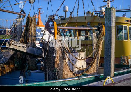 Trascina la rete su una barca da pesca di granchio ormeggiata con catene di ferro arrugginite durante il tramonto Foto Stock