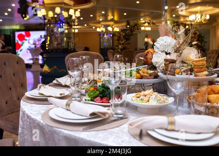 Tovaglioli bianchi, splendidamente ripiegati su piatti in un ristorante. Interno del ristorante Foto Stock