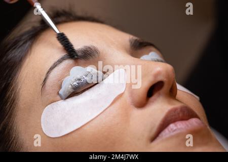 Primo piano del viso di una donna durante un trattamento di ispessimento delle sopracciglia e di laminazione delle ciglia. concetto di professionalità dell'estetista del cashmaker Foto Stock