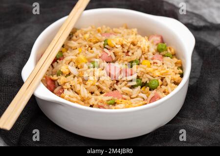 Riso con mais. piselli, prosciutto su ciotola bianca piccola Foto Stock