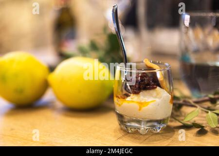 Un poco profondo colpo di fuoco di una mousse cremosa con frutta secca in esso con limoni sullo sfondo Foto Stock